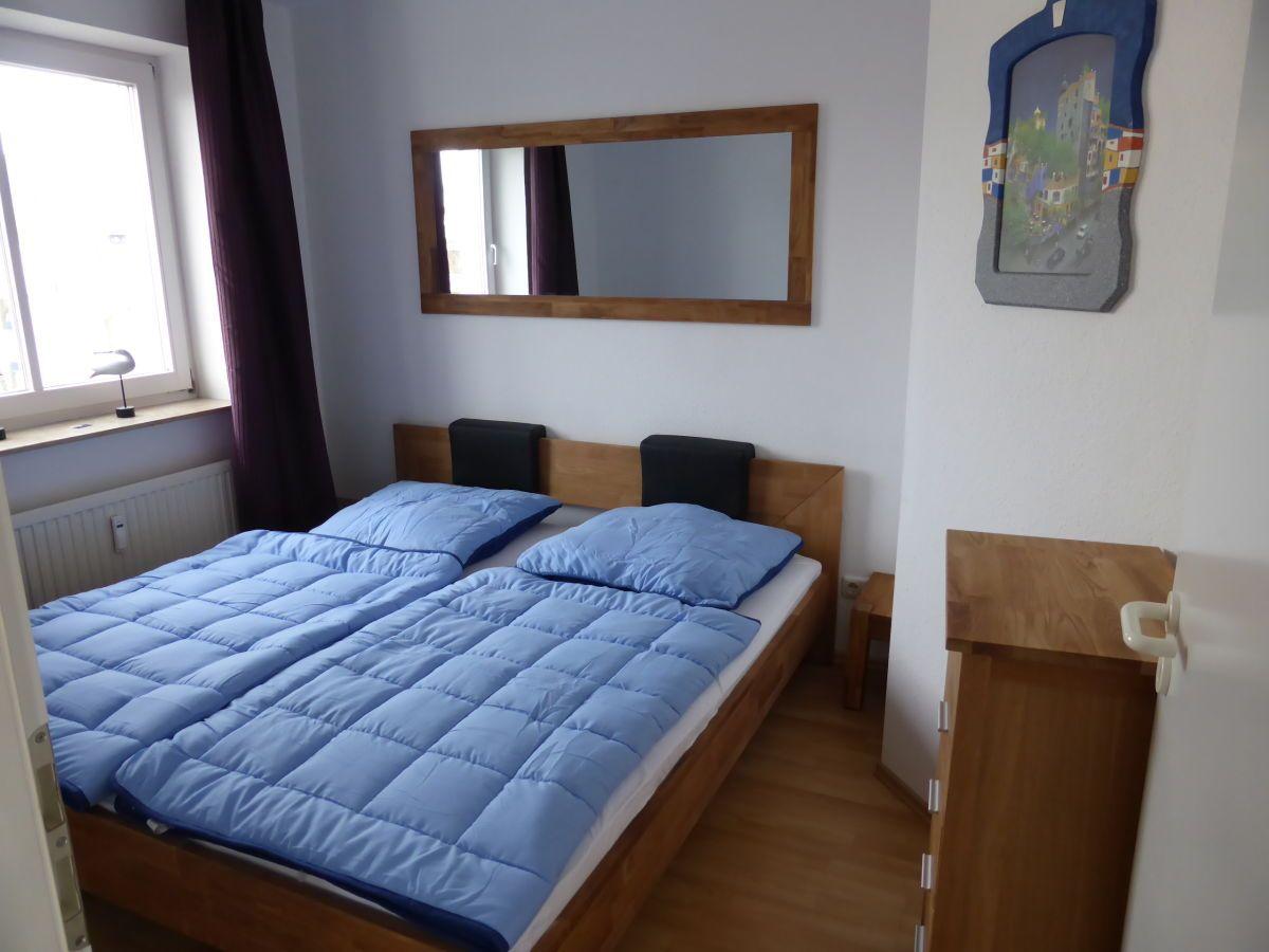 Schlafzimmer mit Doppelbett, Spiegel und Holzmöbel.