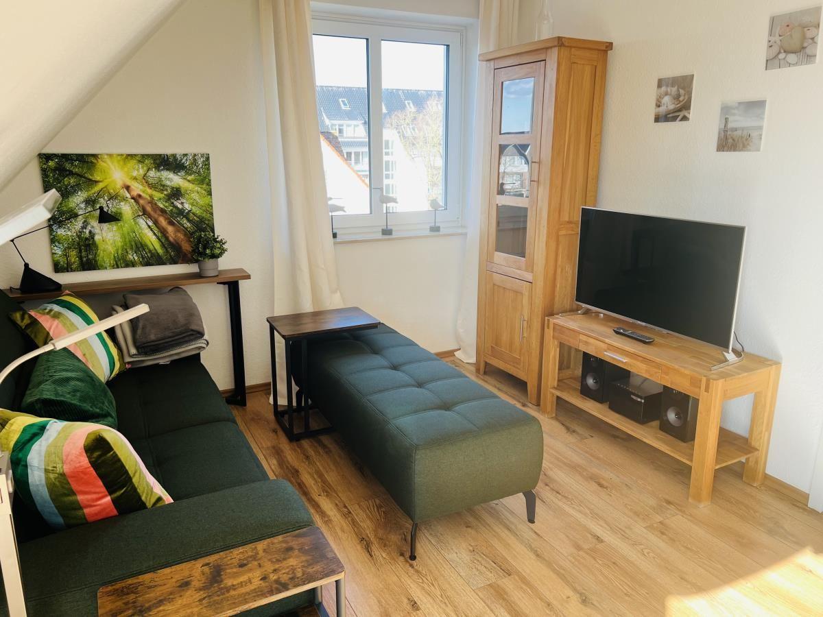 Wohnzimmer mit Sofa, Sitzbank, Fernseher und Holzmöbeln.