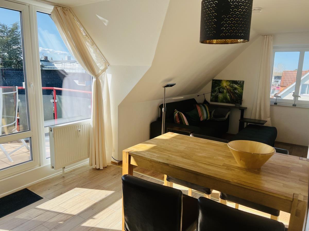 Doppelzimmer mit Balkon, Esstisch und Sofa unter Dachschrägen.