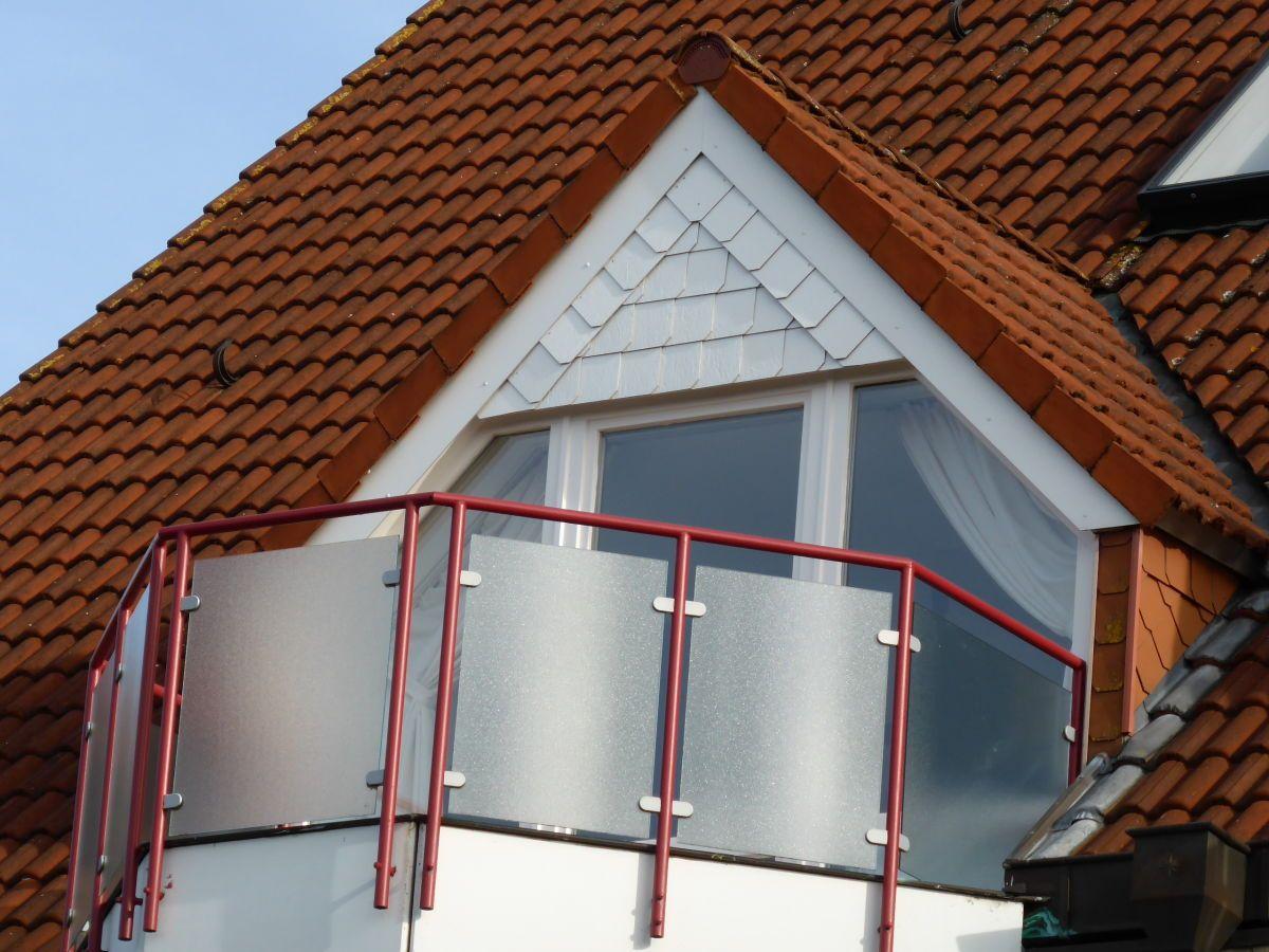 Dachgeschoss balkon mit roten metallgeländer und getöntem glas
