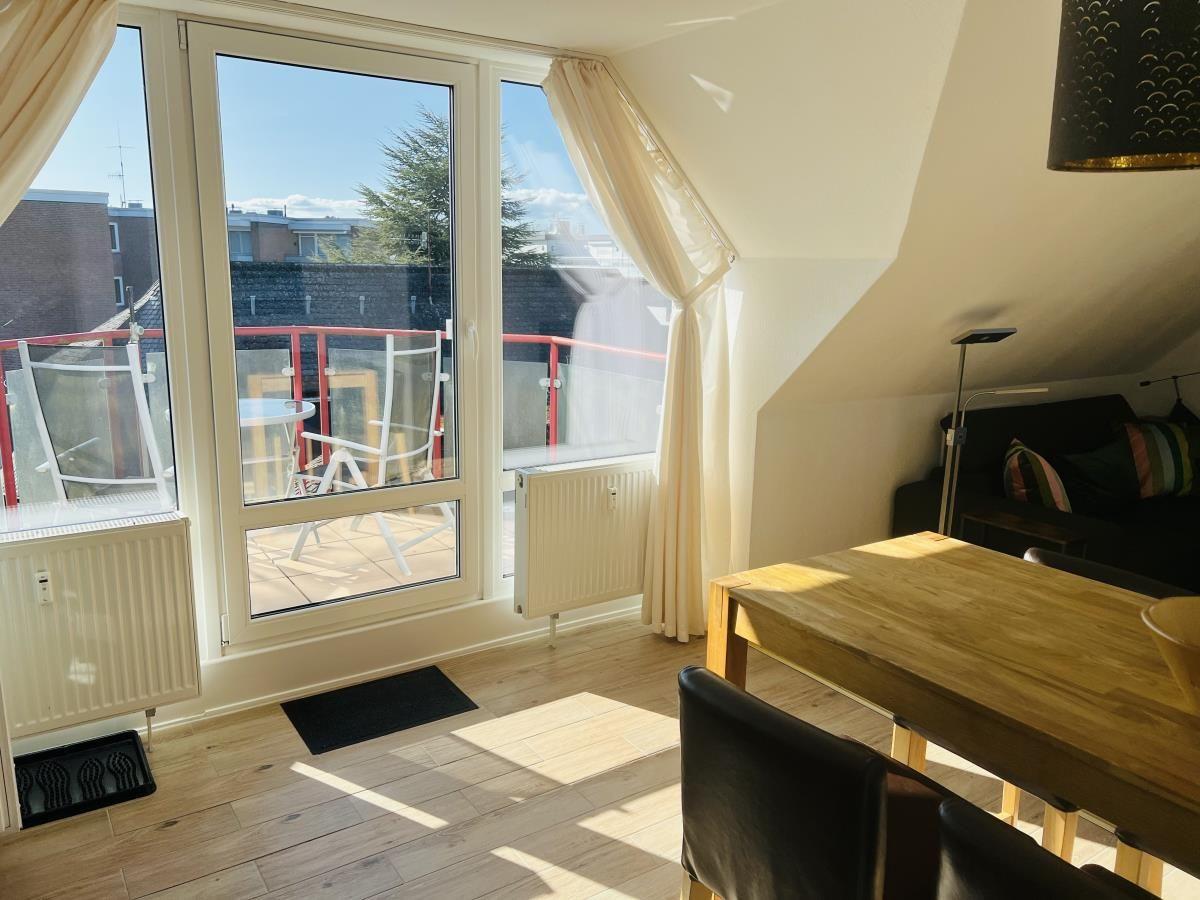 Wohnung mit Balkon, Essbereich und Schlafzimmer. Holzdielen und große Fenster.