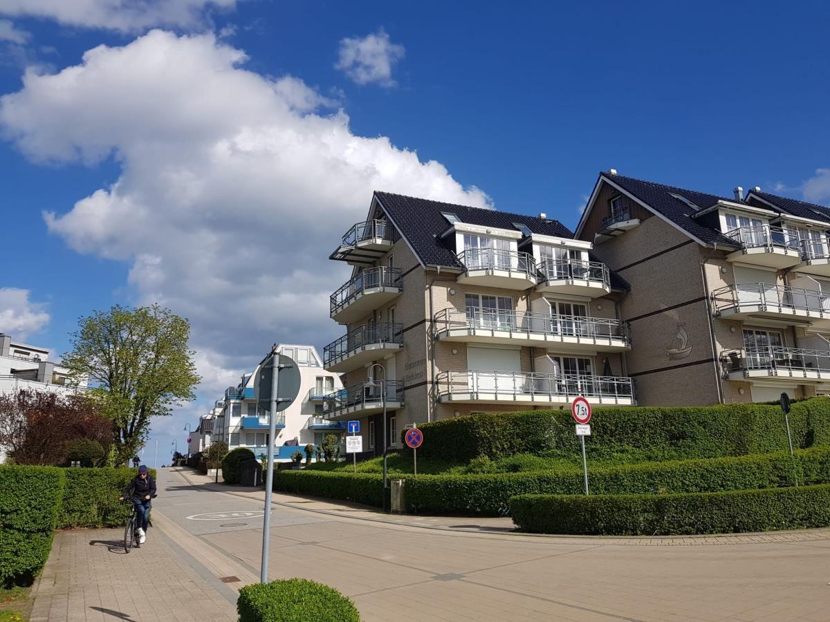 Moderne Mehrfamilienhäuser mit Balkonen und gepflegten Hecken an einer Straße.