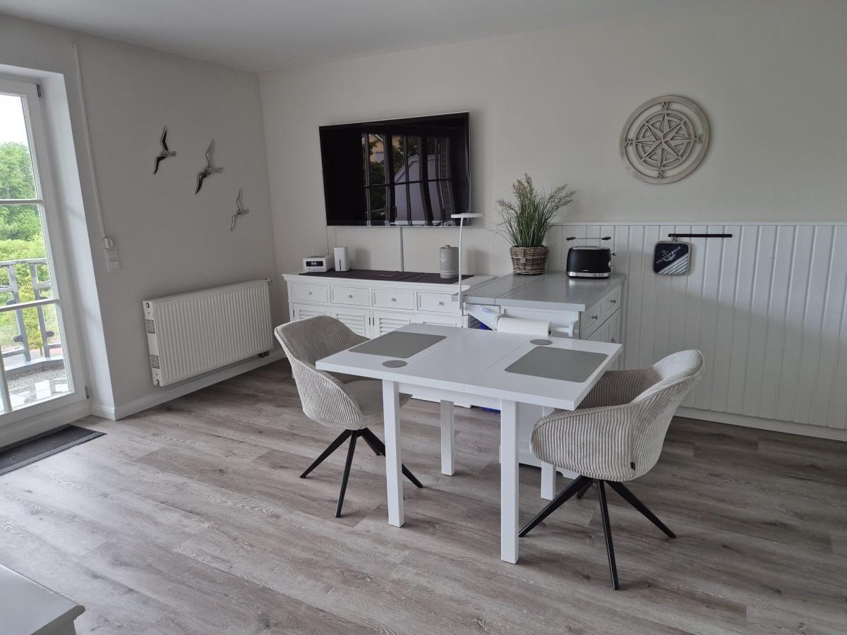 Esszimmer mit Tisch, Stühlen und Fernseher an der Wand
