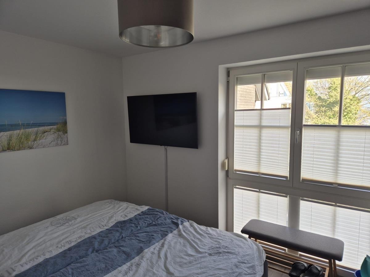 Schlafzimmer mit Bett, TV und Fenster mit Jalousien.