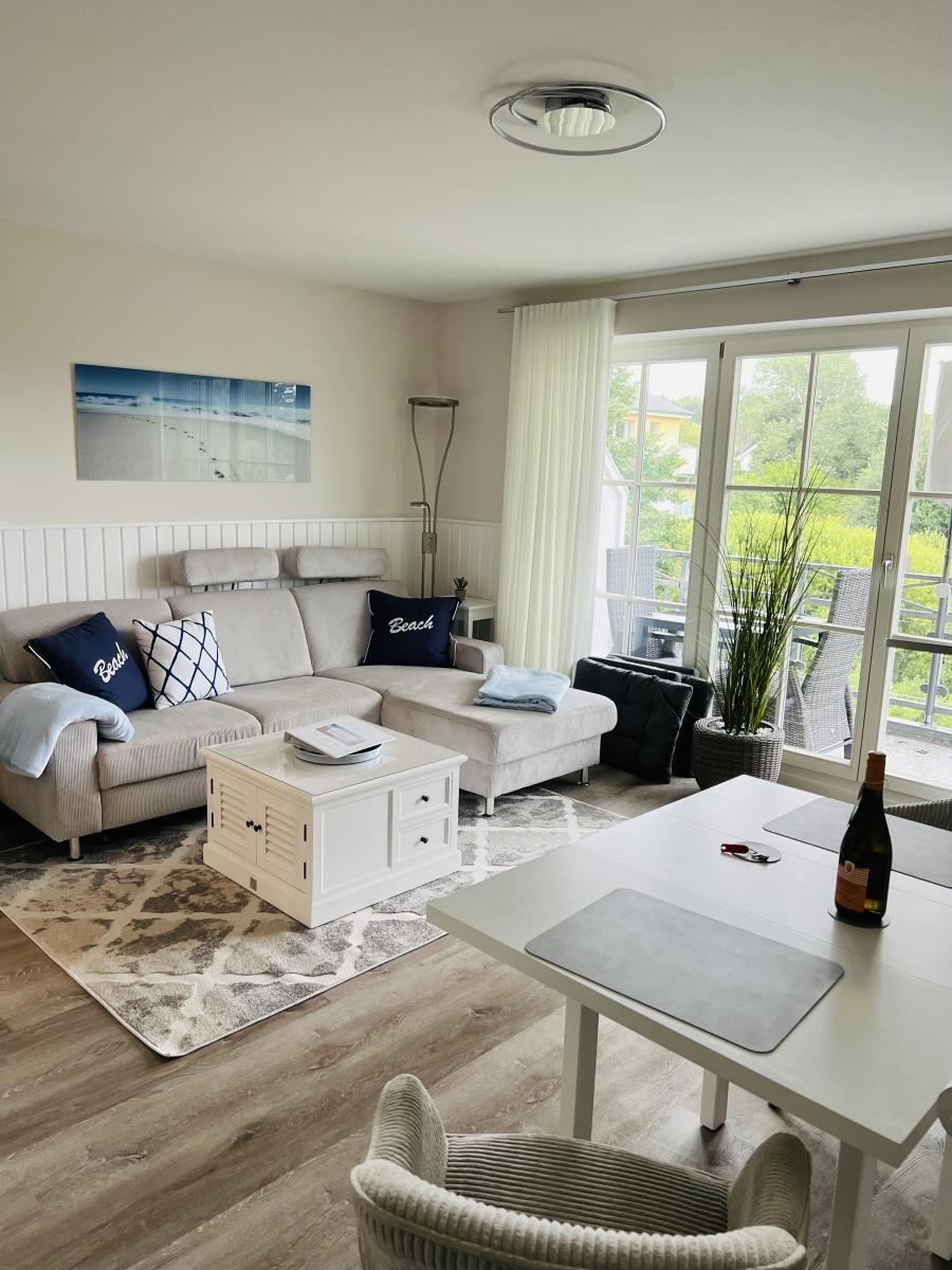 Wohn- und Essbereich mit Sofa, Tisch und Blick auf Balkon.
