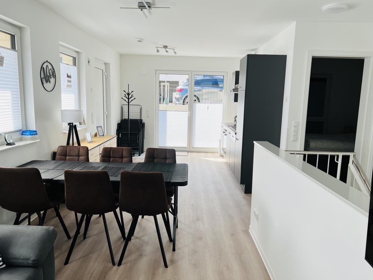 Dining area with table and chairs, kitchen and bedroom in the background.