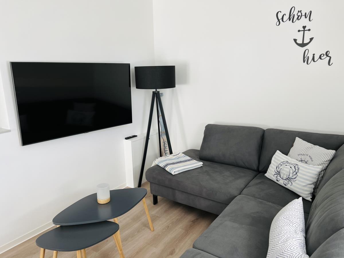 Gray sofa with pillows, wall TV, and floor lamp in living room.