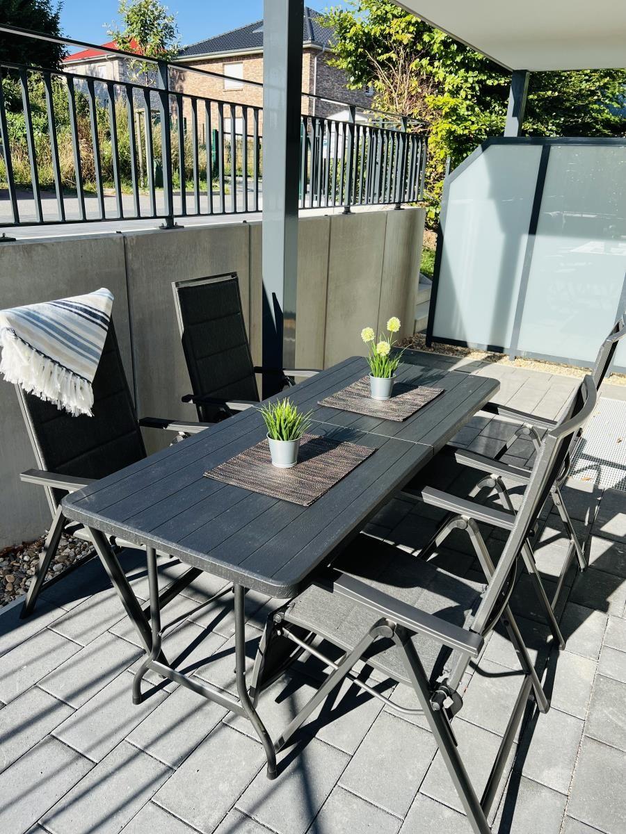 Terrace with table, chairs, plants, and sunshade.