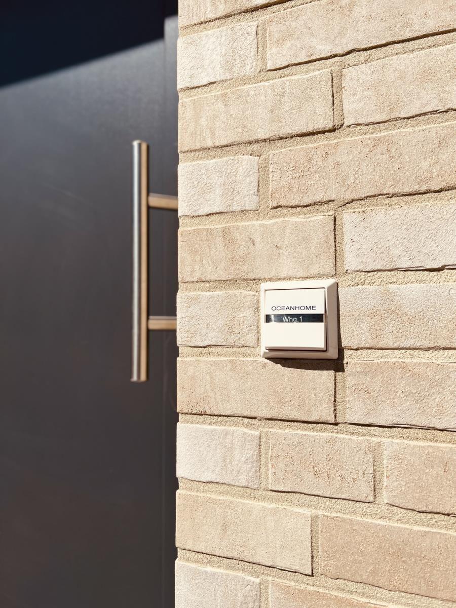 Unit Whg.1 with nameplate on stone wall beside dark door.