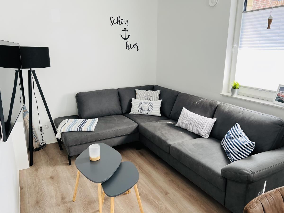 Living room with gray sofa, decorative cushions, and wooden floor.