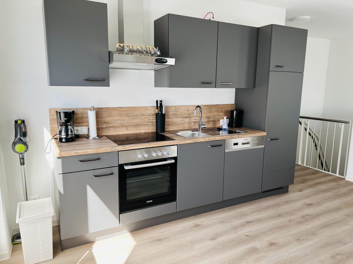 Modern kitchen with gray cabinets, wooden countertop, and built-in stove.