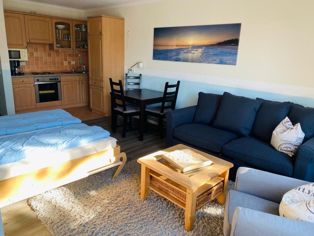 Wohnung mit Schlafzimmer, Küchenzeile und Wohnbereich mit Sofa und Esstisch.