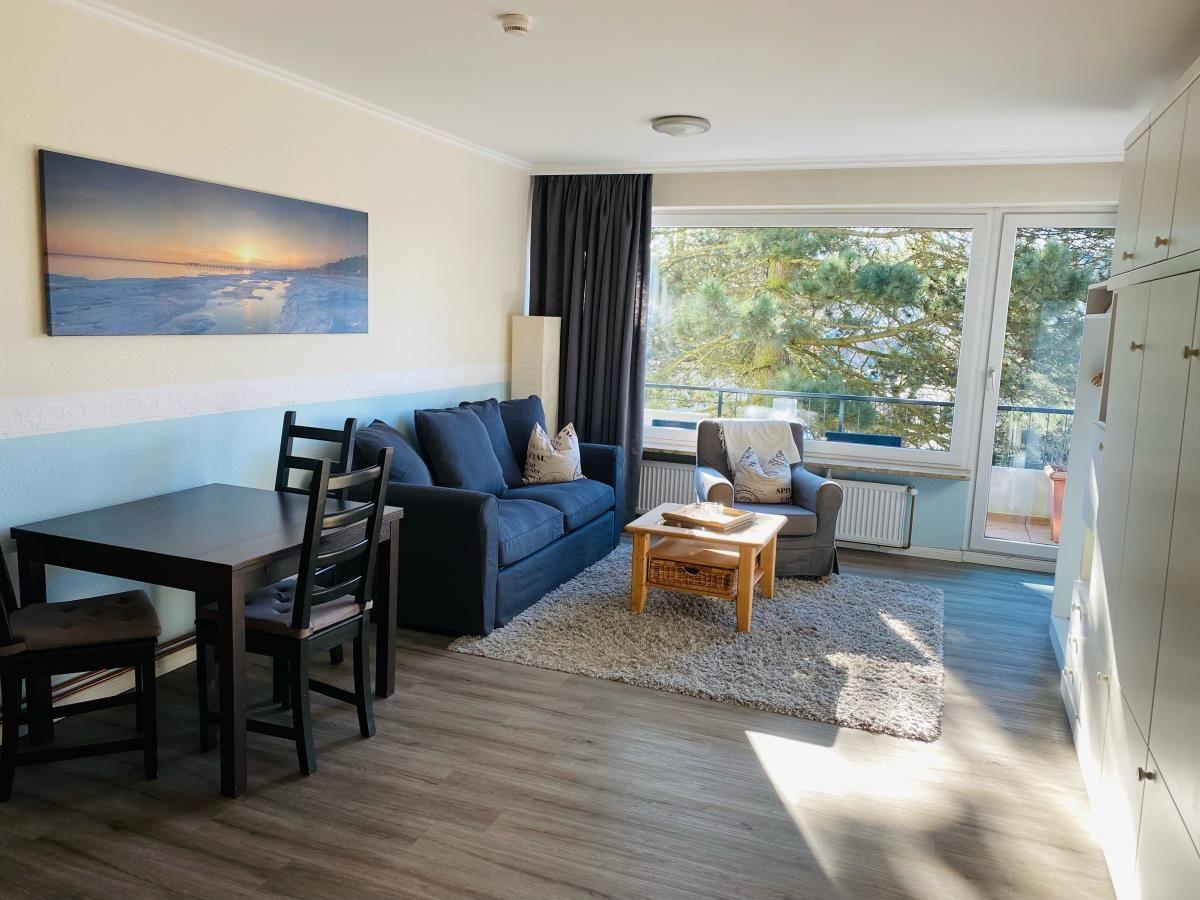 Wohnzimmer mit Sofa, Esstisch und Balkonansicht.