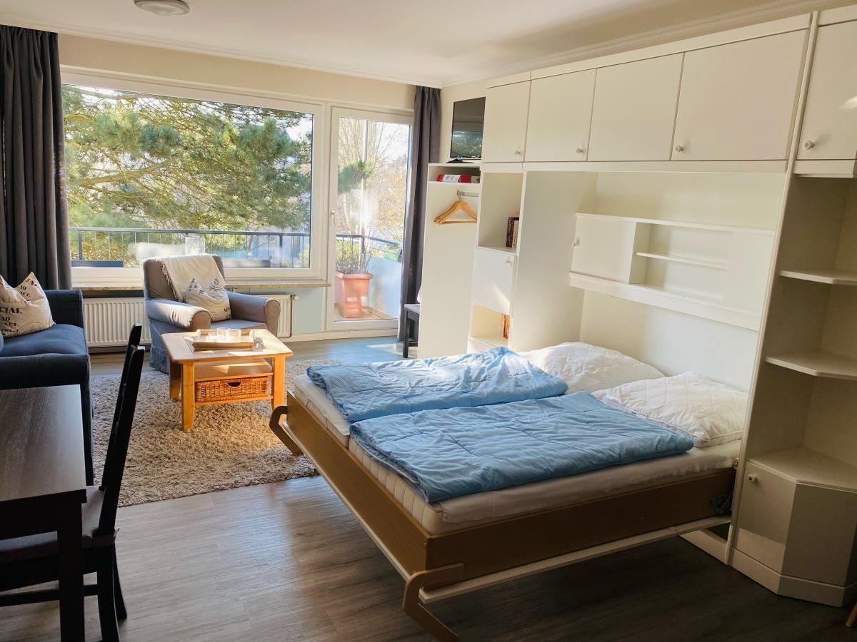 Schlafzimmer mit Bett, Schrank und Balkonblick