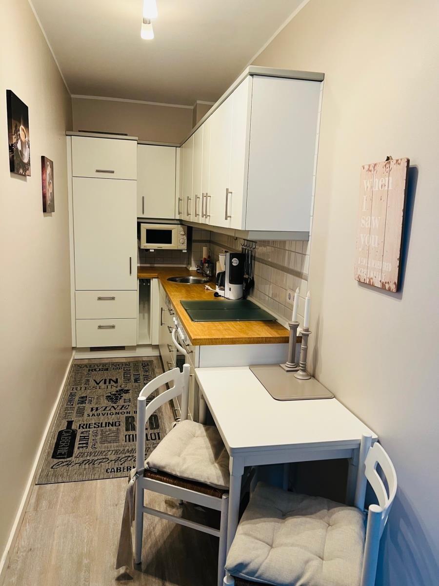 Küche mit Arbeitsplatte, Spüle und Essplatz mit Stühlen.