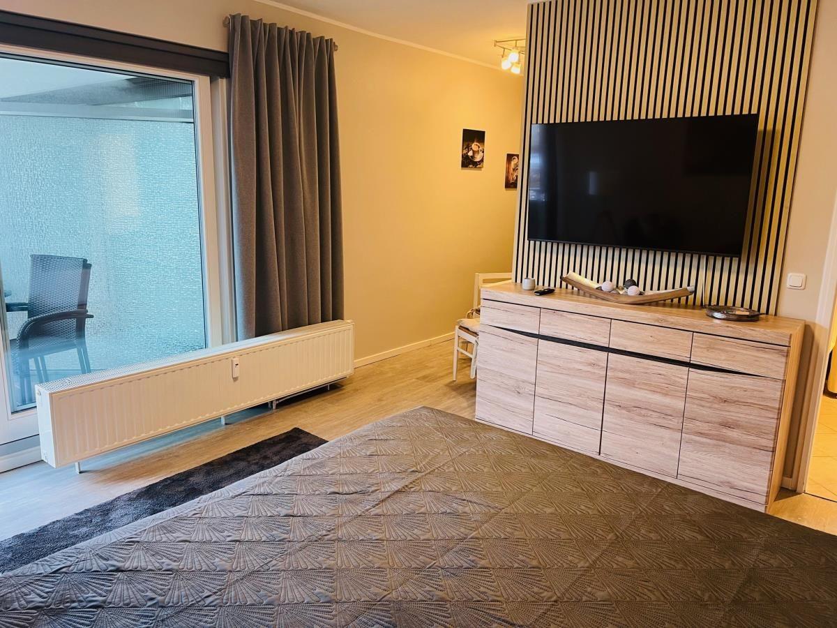 Schlafzimmer mit Bett, TV und Balkonzugang.