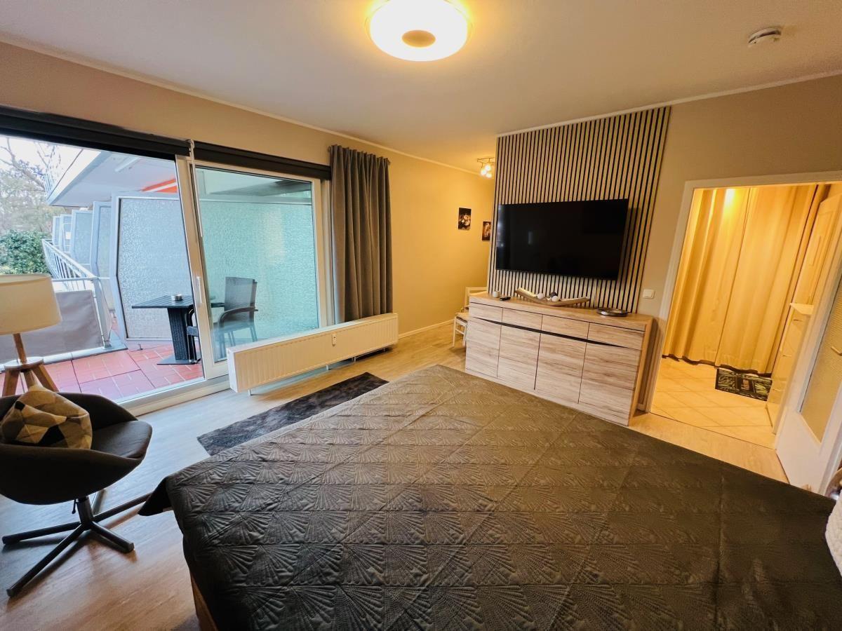 Schlafzimmer mit Bett, TV und Balkonzugang.