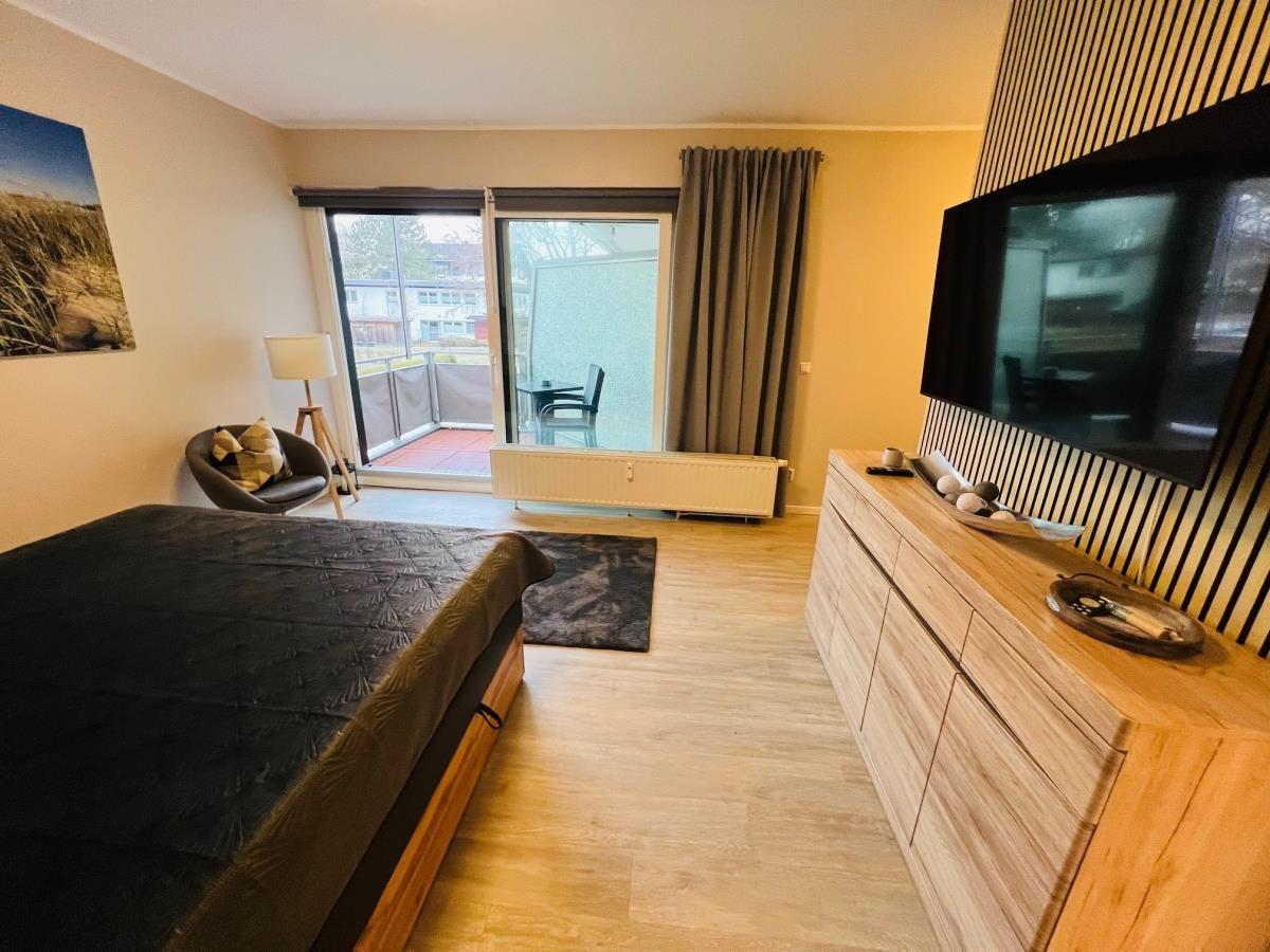 Schlafzimmer mit Bett, TV und Balkonansicht.