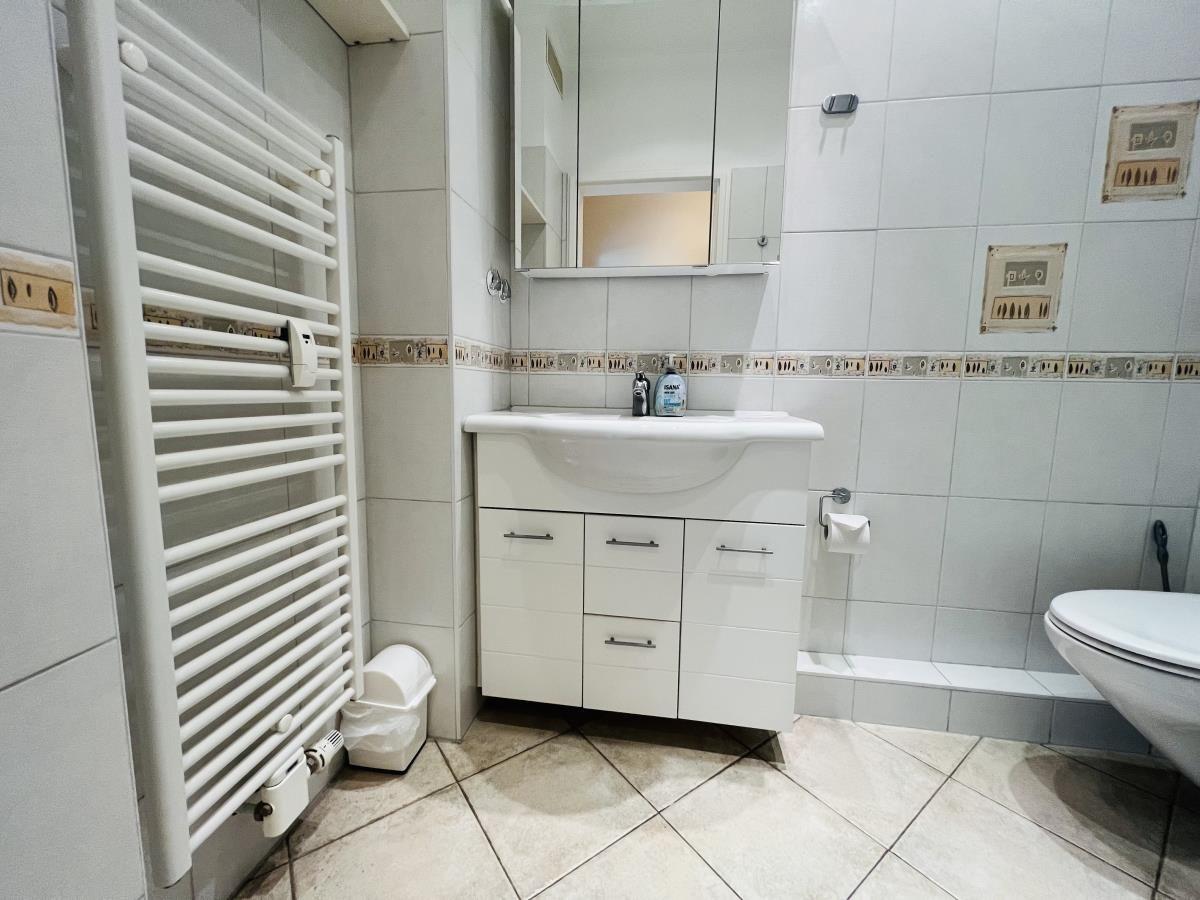 Badezimmer mit Waschbecken, Spiegelschrank, Heizkörper und Toilette.