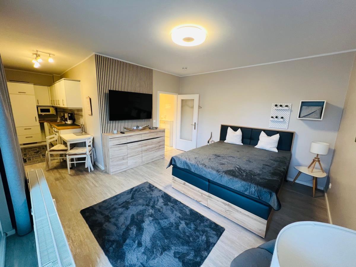 Schlafzimmer mit Bett, Fernseher und Küchenbereich.