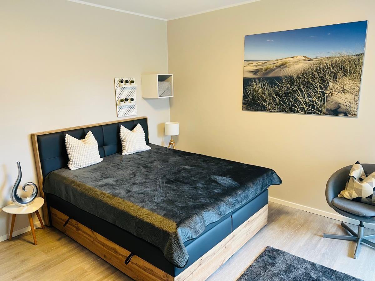 Schlafzimmer mit Bett, Wandbild und Sitzgelegenheit.