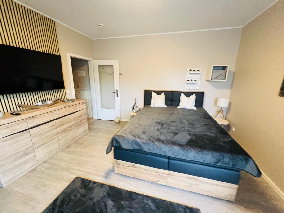 Schlafzimmer mit Bett, TV und Holzmöbeln