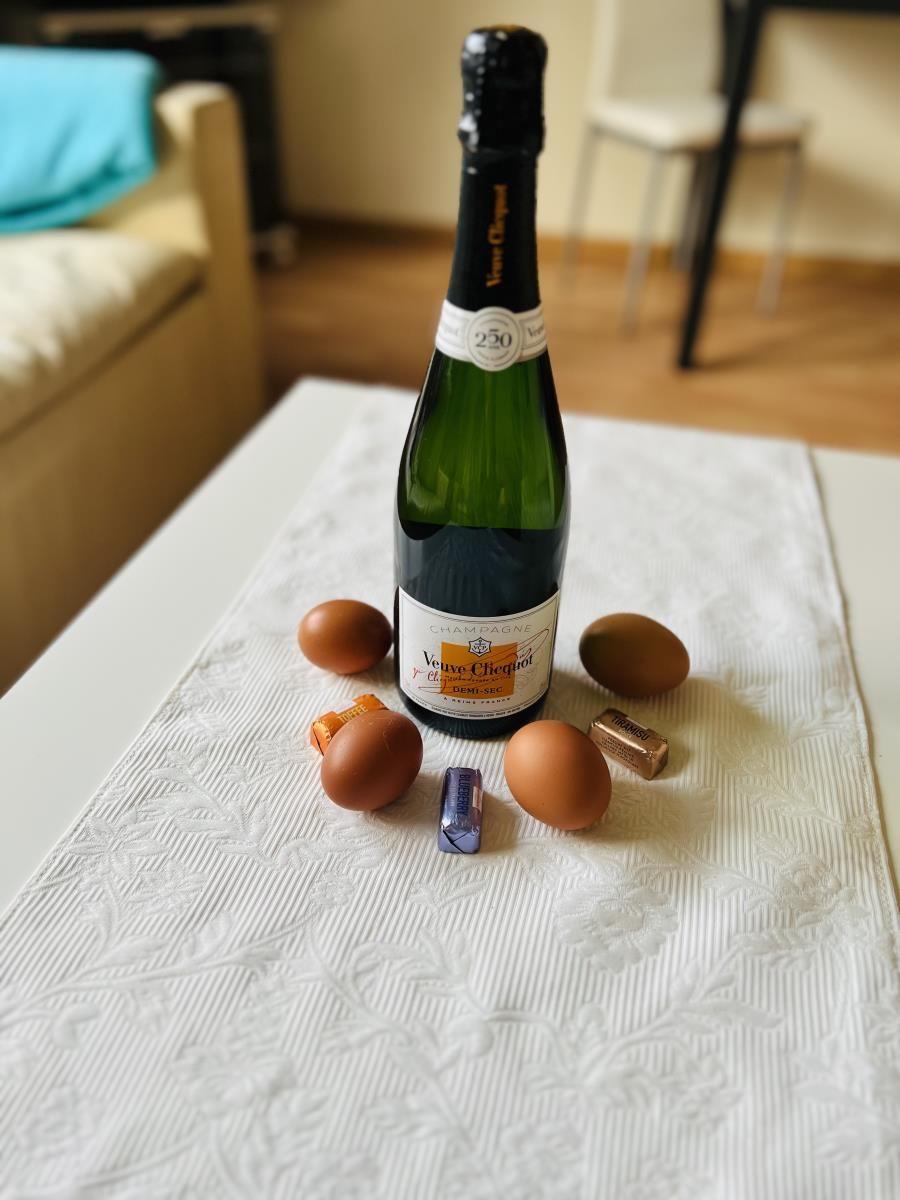 Auf Tisch mit Tischdecke steht Champagner, Eier und Schokolade.