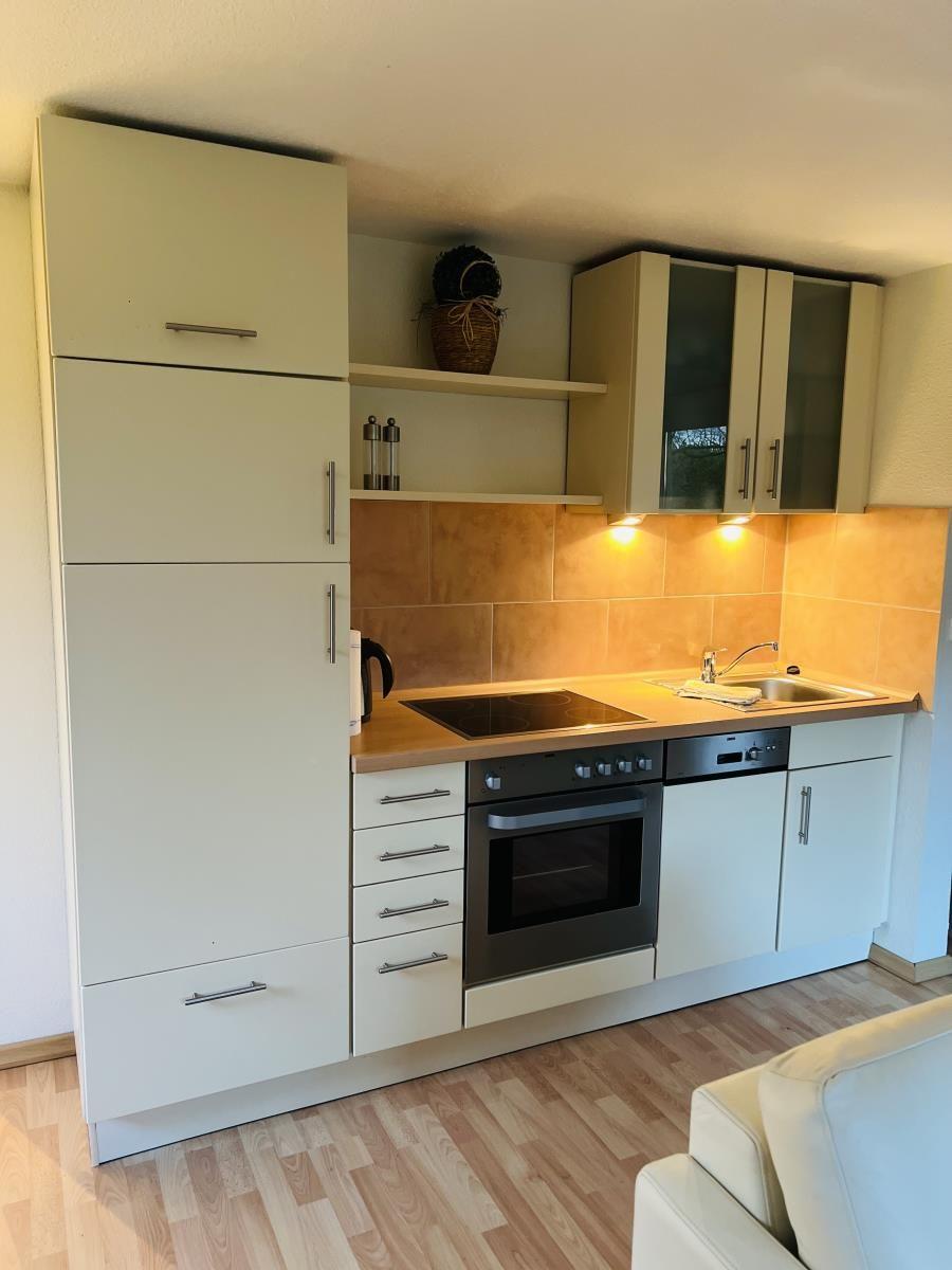 Küche mit Schränken, Herd, Spüle und Holzboden.