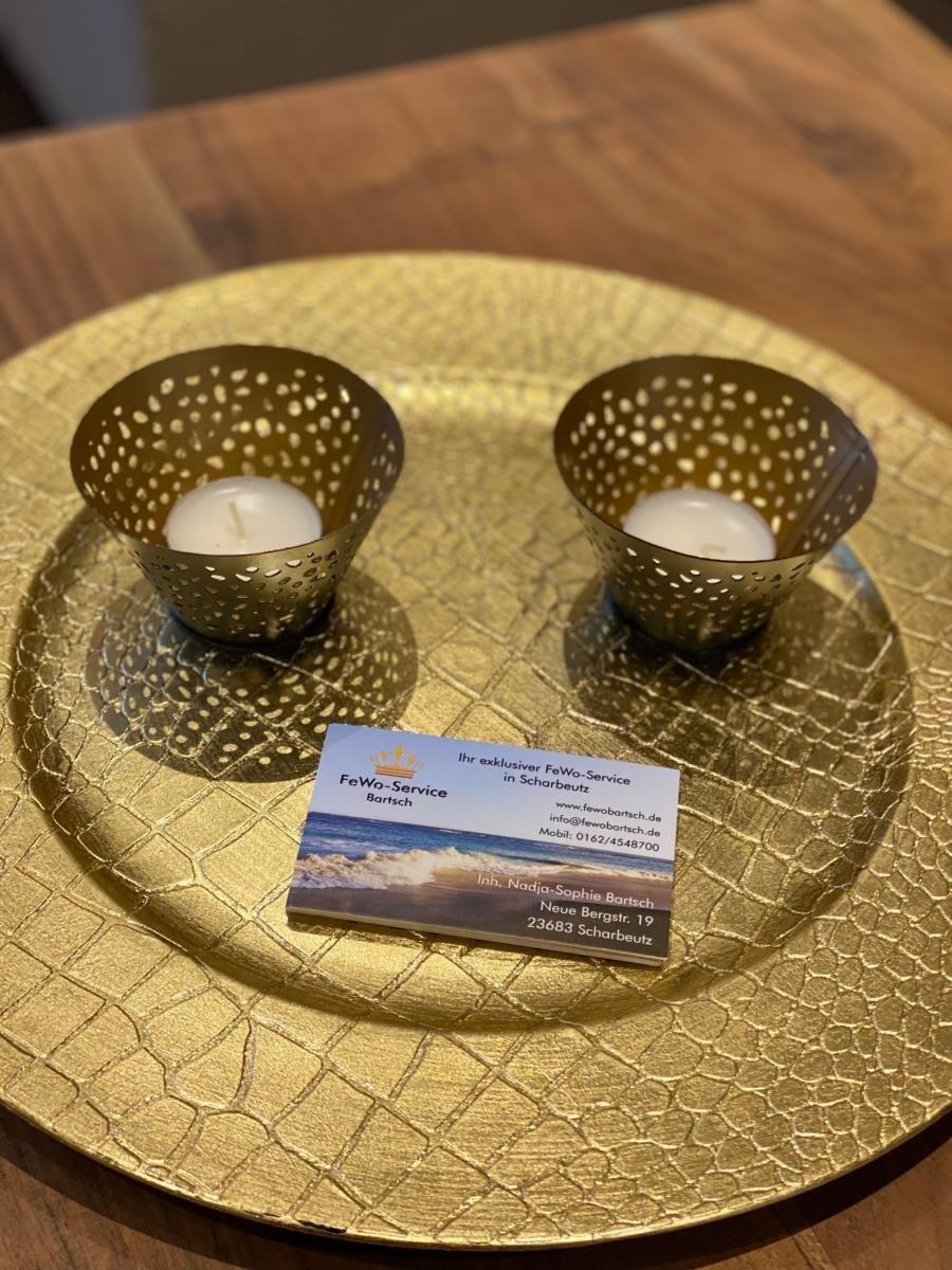 Goldener Teller mit zwei Kerzenhaltern und Visitenkarte.