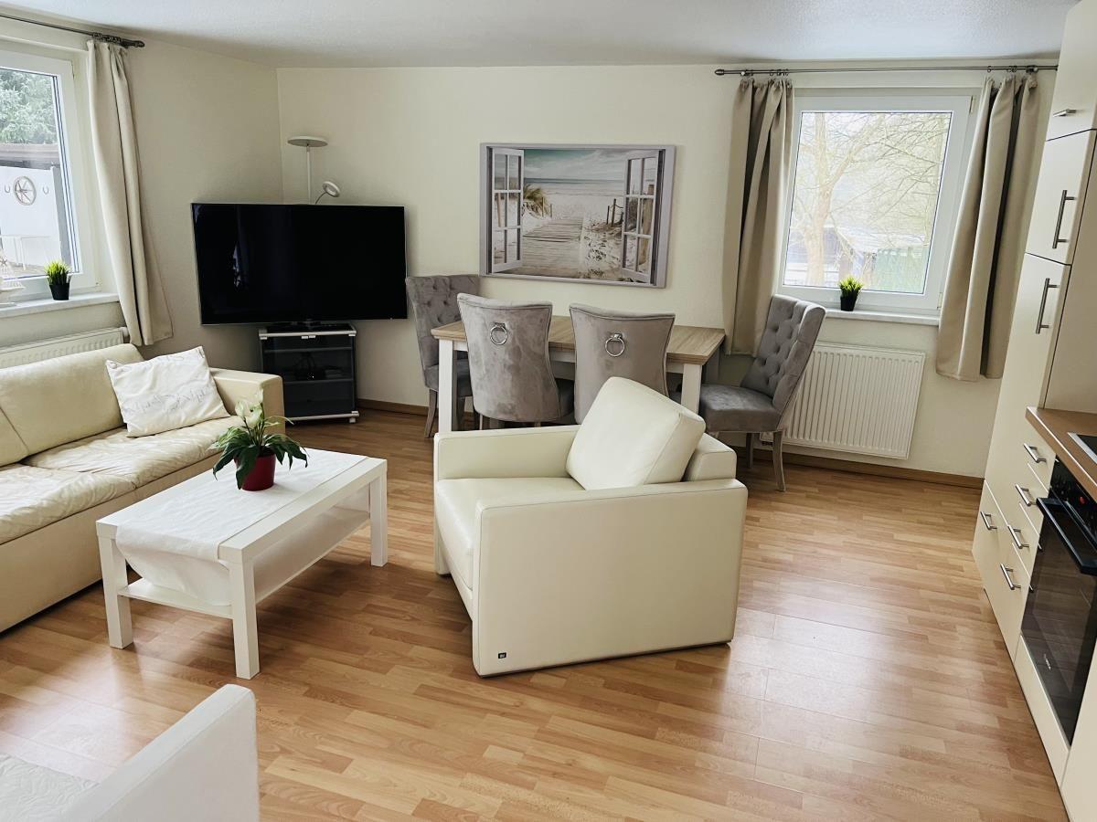 Wohn- und Essbereich mit Sofa, Sessel, Esstisch und TV.