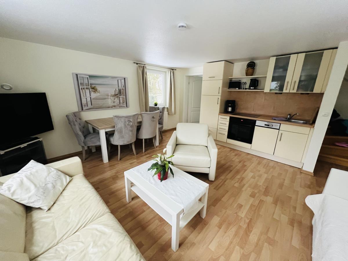 Wohnung mit Küche, Essbereich und Wohnzimmer mit Holzboden und weißen Möbeln.