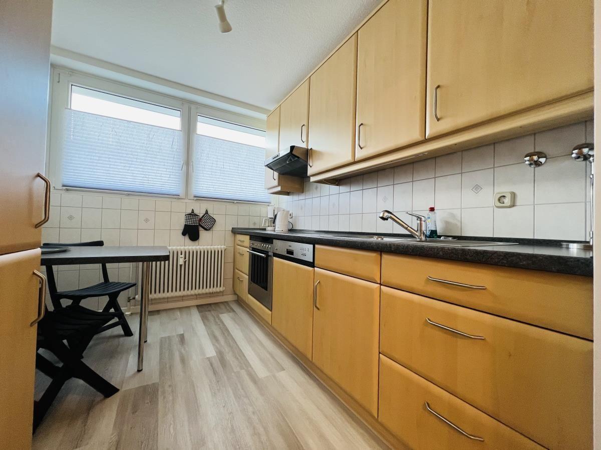 Küche mit Holzschränken, Arbeitsplatte und Fenster