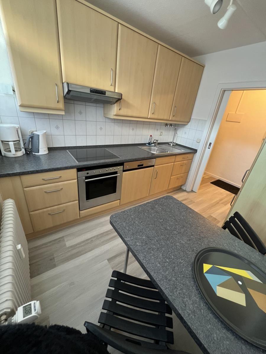 Küche mit Holzschränken, Edelstahlgeräten und Essbereich.