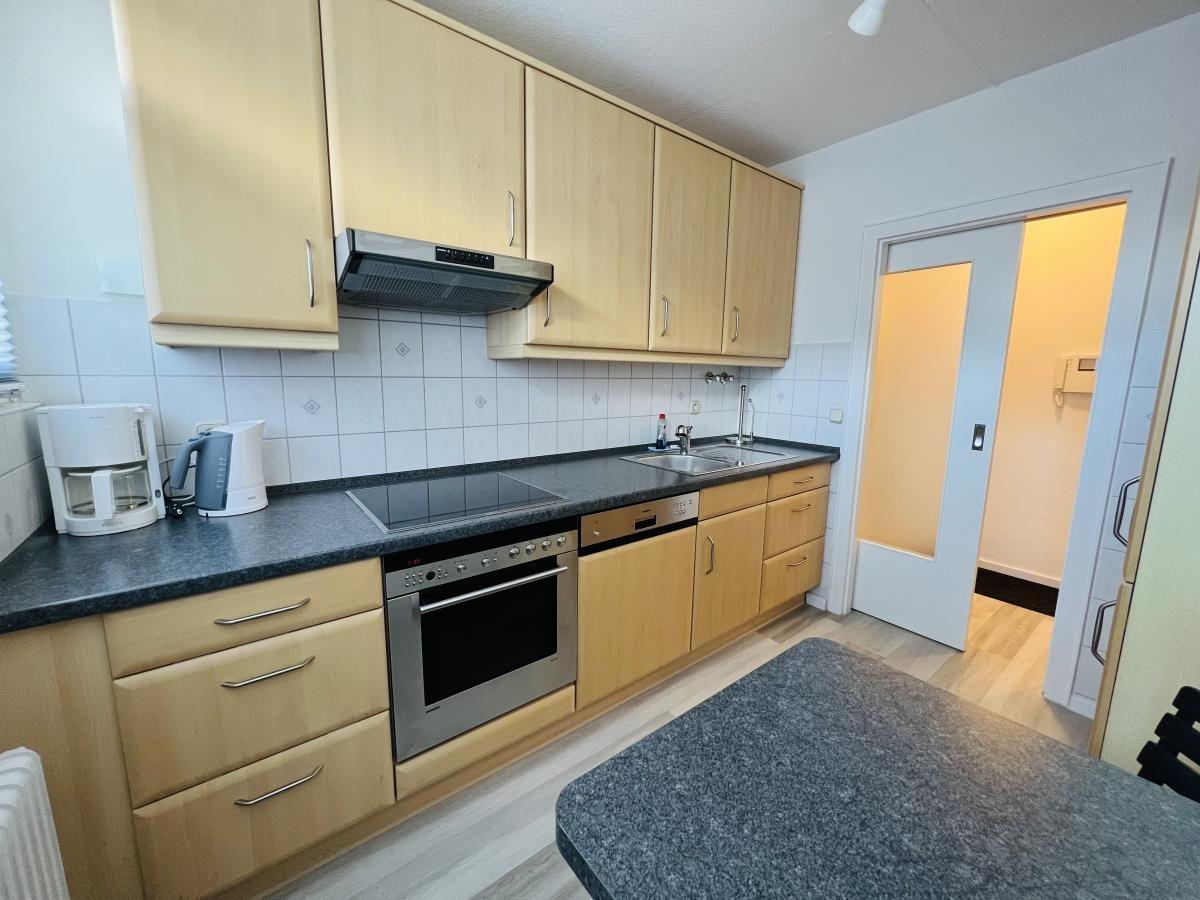 Küche mit Holzschränken, Edelstahlherd und Arbeitsplatte.