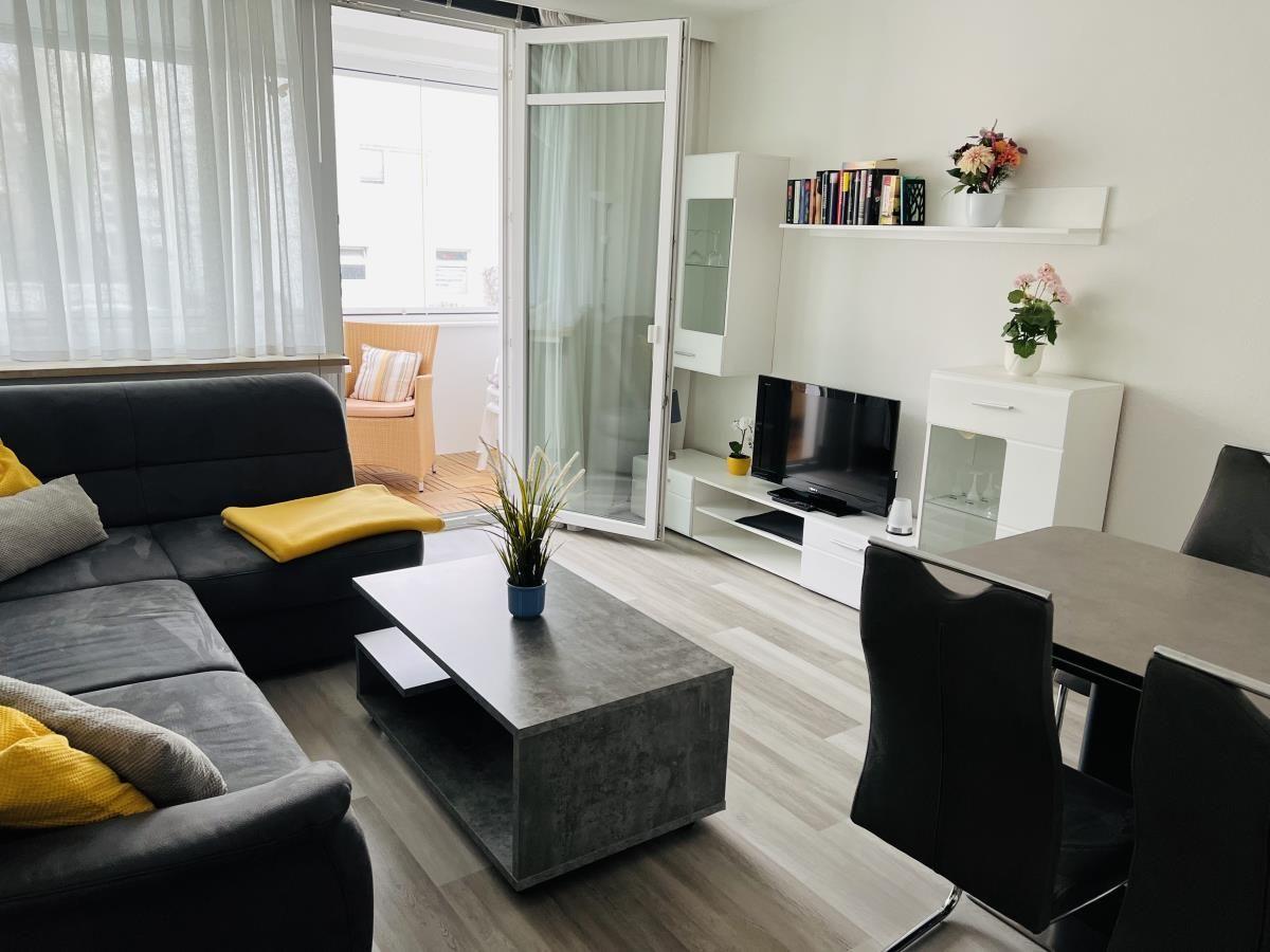 Wohn- und Essbereich mit Sofa, TV und Terrasse.