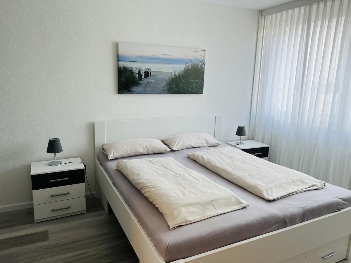 Schlafzimmer mit Doppelbett, zwei Nachttischen und Wandbild an der Wand.