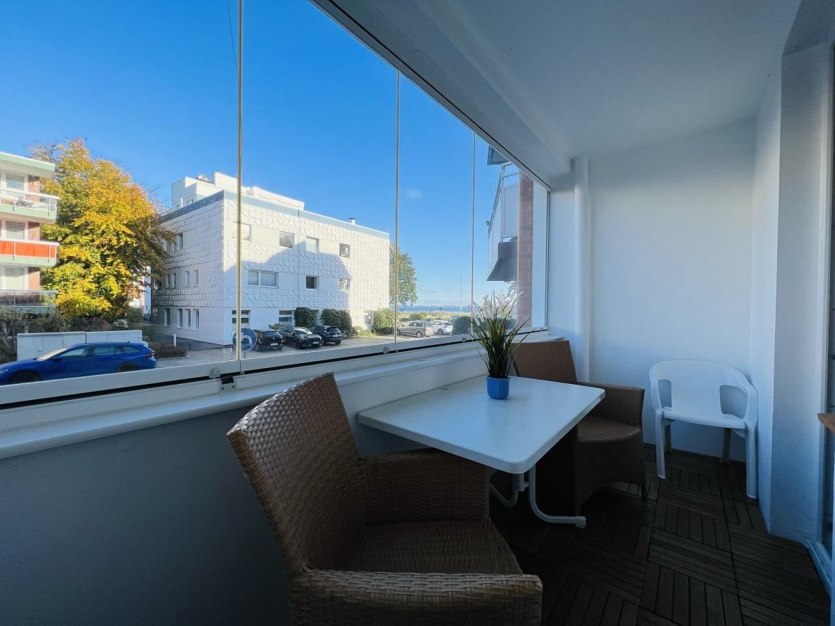 Terrasse mit Tisch, Stühlen und Blick auf Gebäude und Parkplatz.