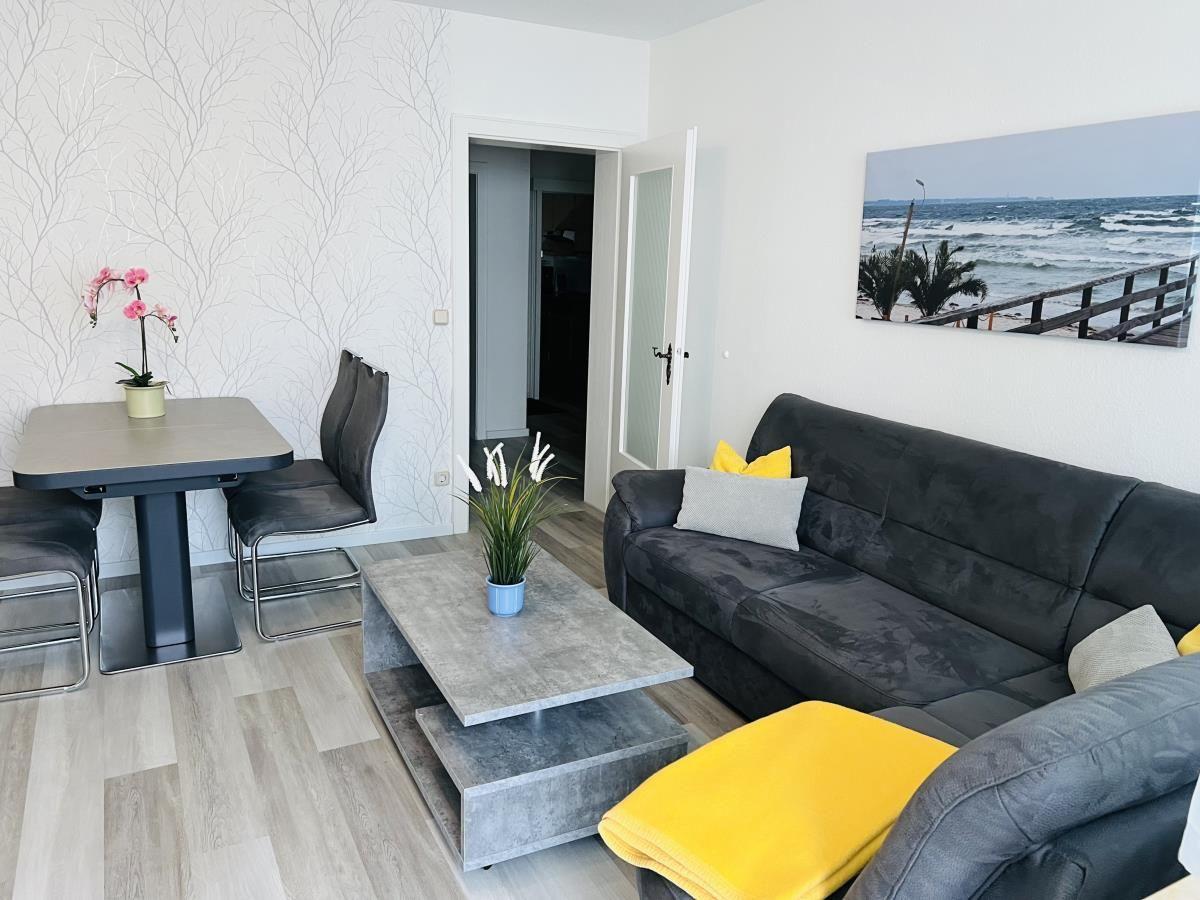 Wohnzimmer mit Sofa, Esstisch und Wandbild an der Wand.