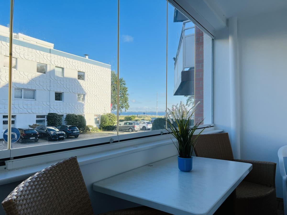 Terrasse mit Tisch und Stühlen, Blick auf Parkplatz und Gebäude.