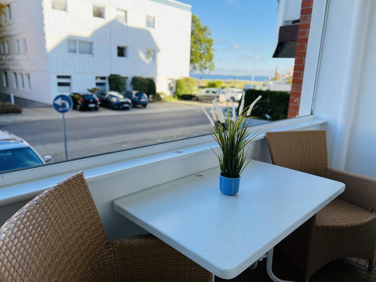 Terrasse mit Tisch und Stühlen. Blick auf Straße und Gebäude.