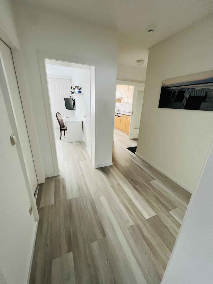 Flur mit Holzboden führt in Küche und Arbeitszimmer.