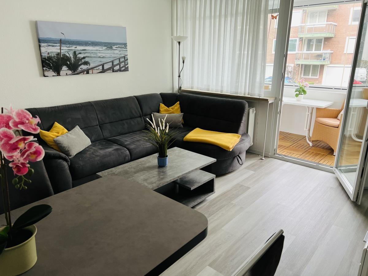 Wohnzimmer mit Sofa, Couchtisch und Balkonzugang.