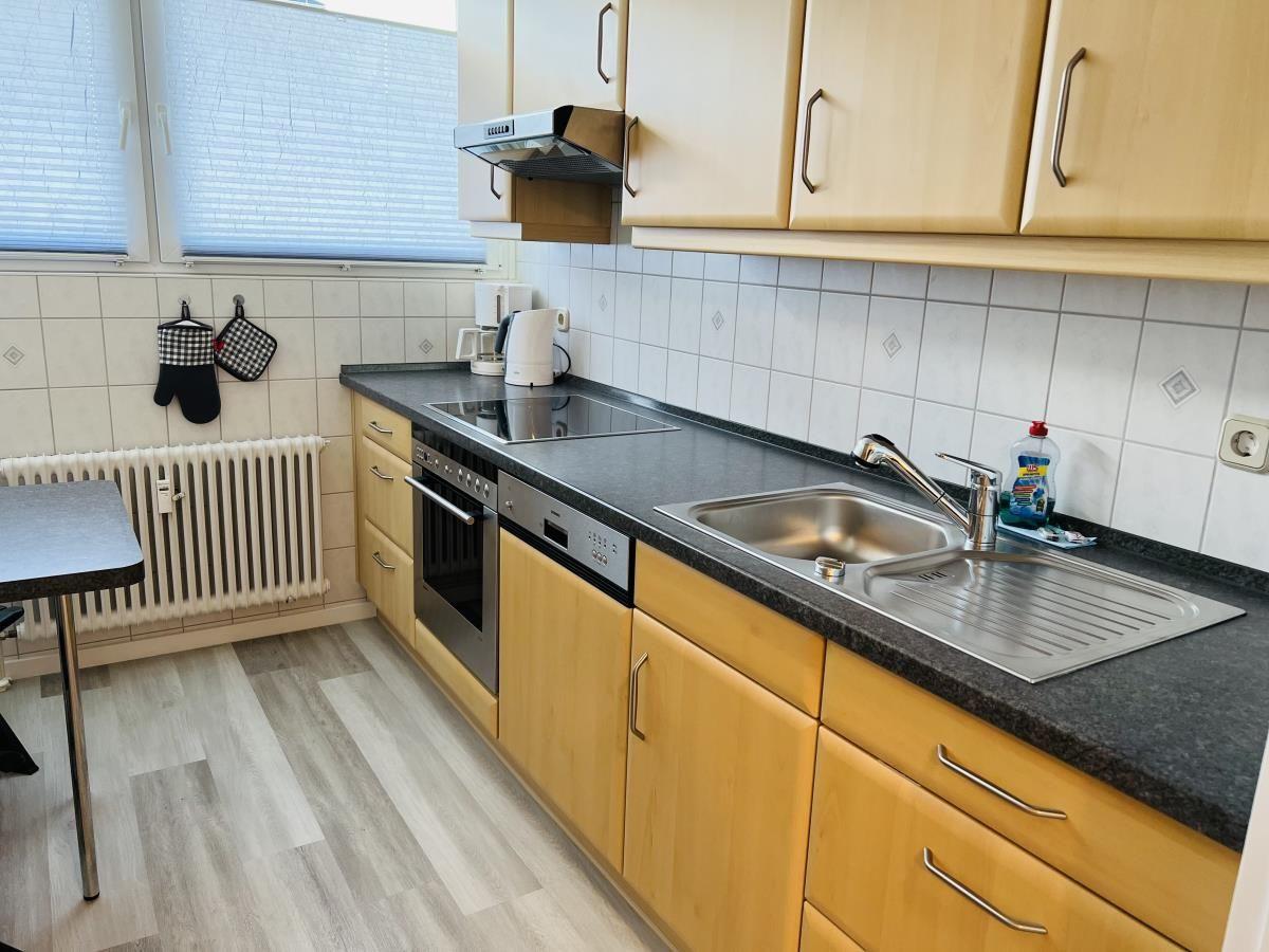 Küche mit Holzschränken, Edelstahlspüle und Kochfeld.