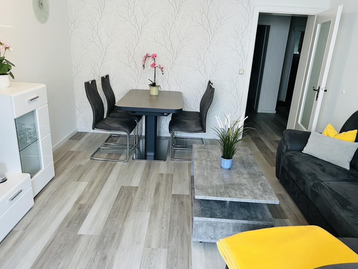 Wohn- und Essbereich mit Tisch, Stühlen, Sofa und Pflanzen.