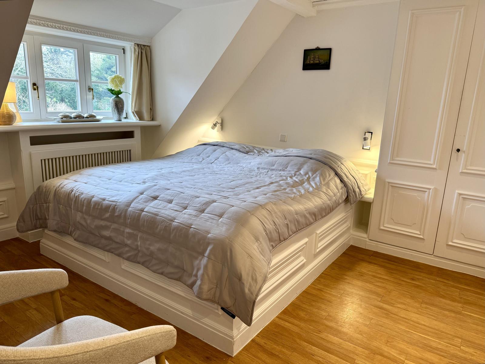 Schlafzimmer mit Dachfenster, Bett und Kleiderschrank.