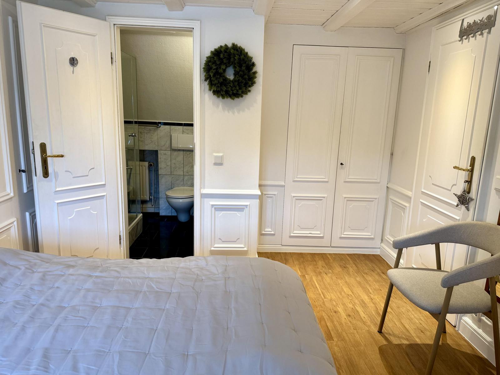 Schlafzimmer mit Bett, Stuhl und Blick in Bad