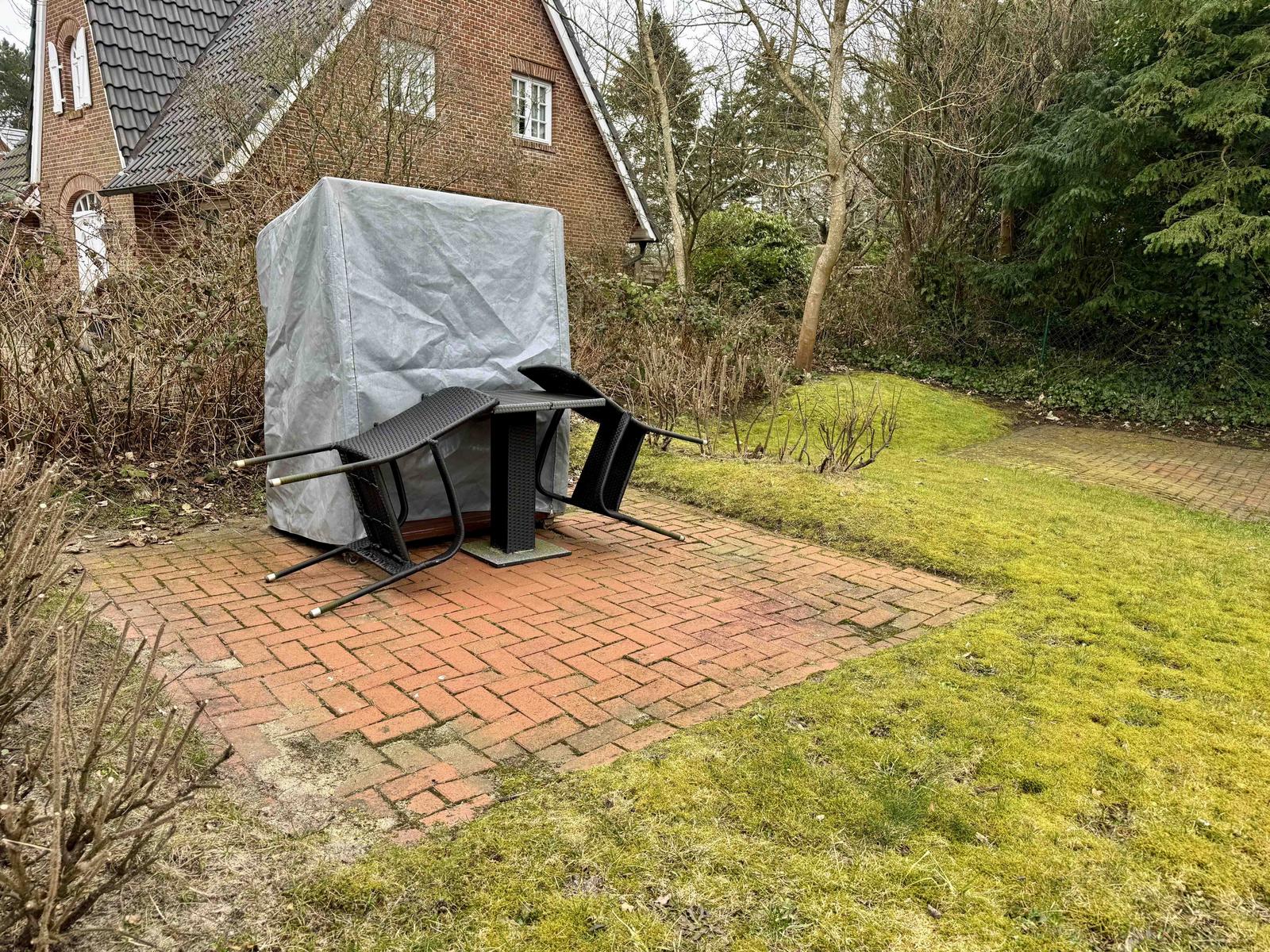 Garten mit Terrasse, gedeckter Sitzbereich und Grünflächen.