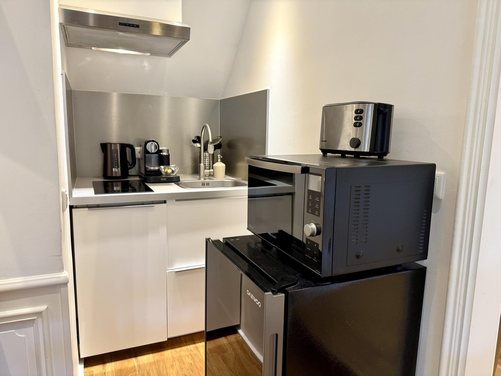 Küche mit Spüle, Kühlschrank, Mikrowelle und Toaster.