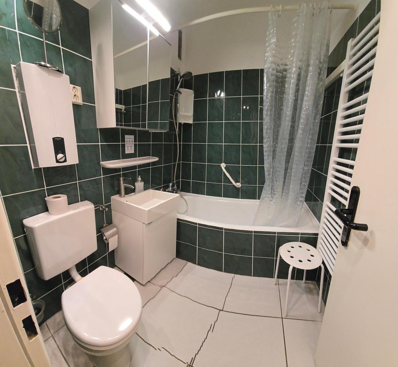 Badezimmer mit Badewanne, Dusche, Toilette und Waschbecken.