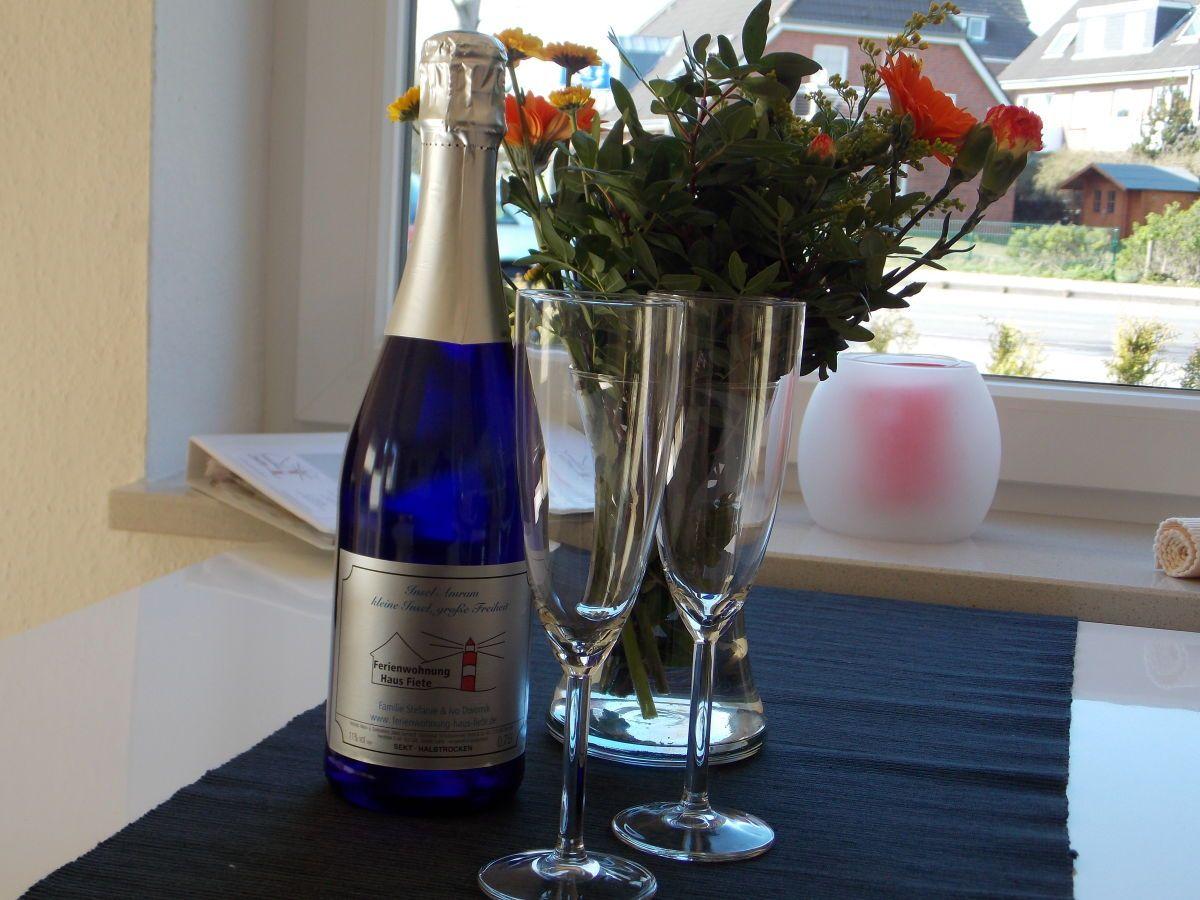 Blauer Sekt, zwei Gläser und Blumen auf Fensterbank.